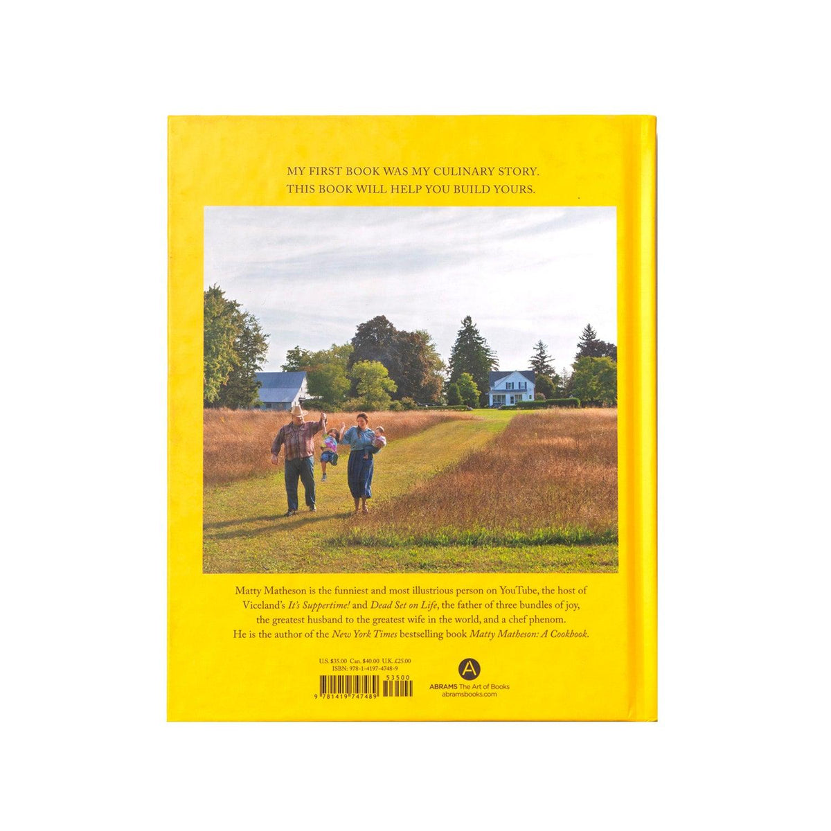 Home Style Cookery Book back cover featuring a bright yellow background with a scenic photograph of a rural landscape, showing a dirt path through golden fields leading to distant farmhouses and trees under an overcast sky