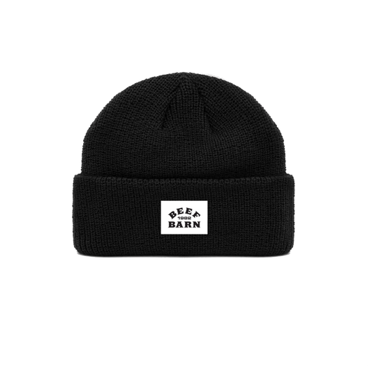 A black acrylic knit beanie with a custom printed tag displaying the text 'BEF BARN' on the front.